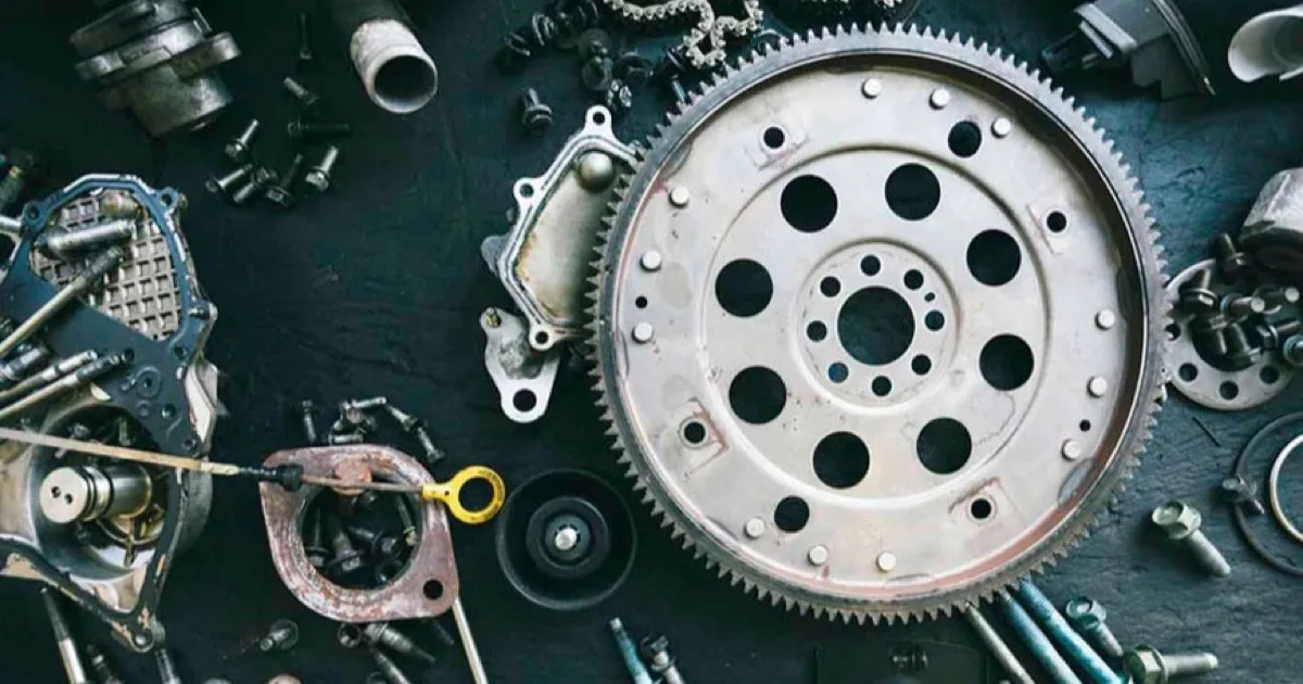 Componentes de aluminio fundidos a presión, como un volante motor y carcasas, sobre una superficie oscura de taller