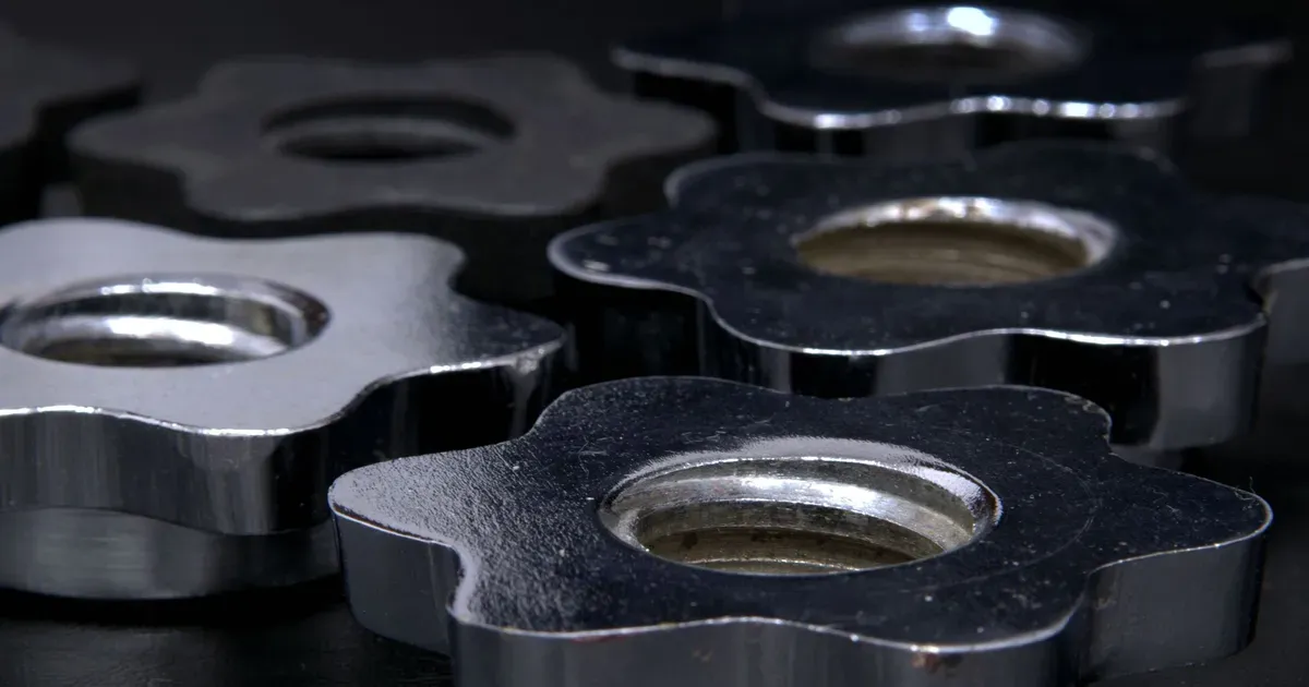 Close-up of shiny die-cast star-shaped clamping knobs with threaded bores on a dark background